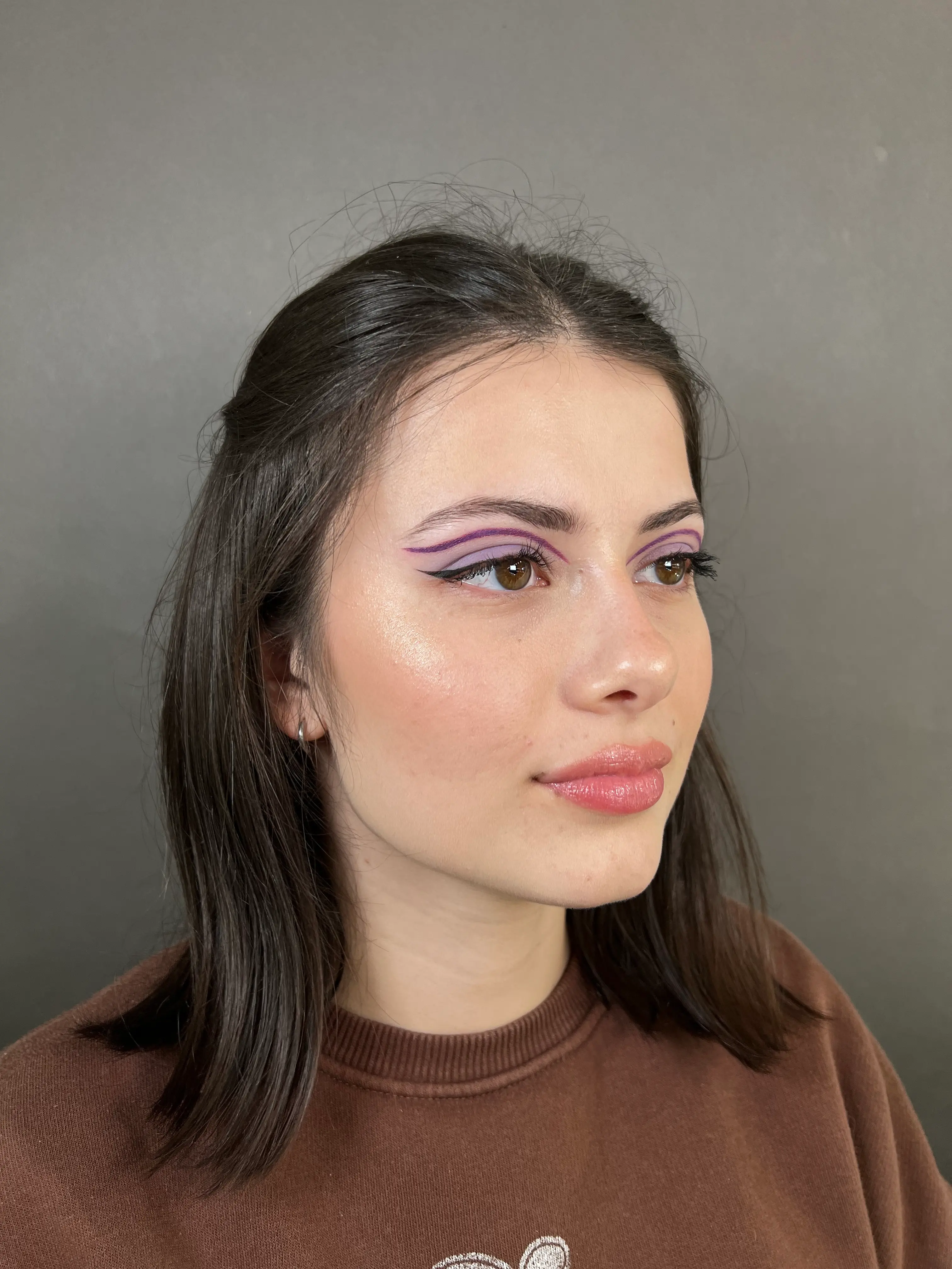 A graphic lilac cat crease that elongates and defines the eyes, paired with fresh, glossy lips.